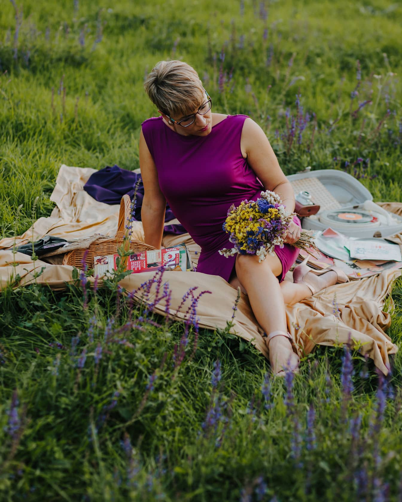 Kaunis nainen nauttii maalaismaisella piknikillä hienossa violetissa mekossa