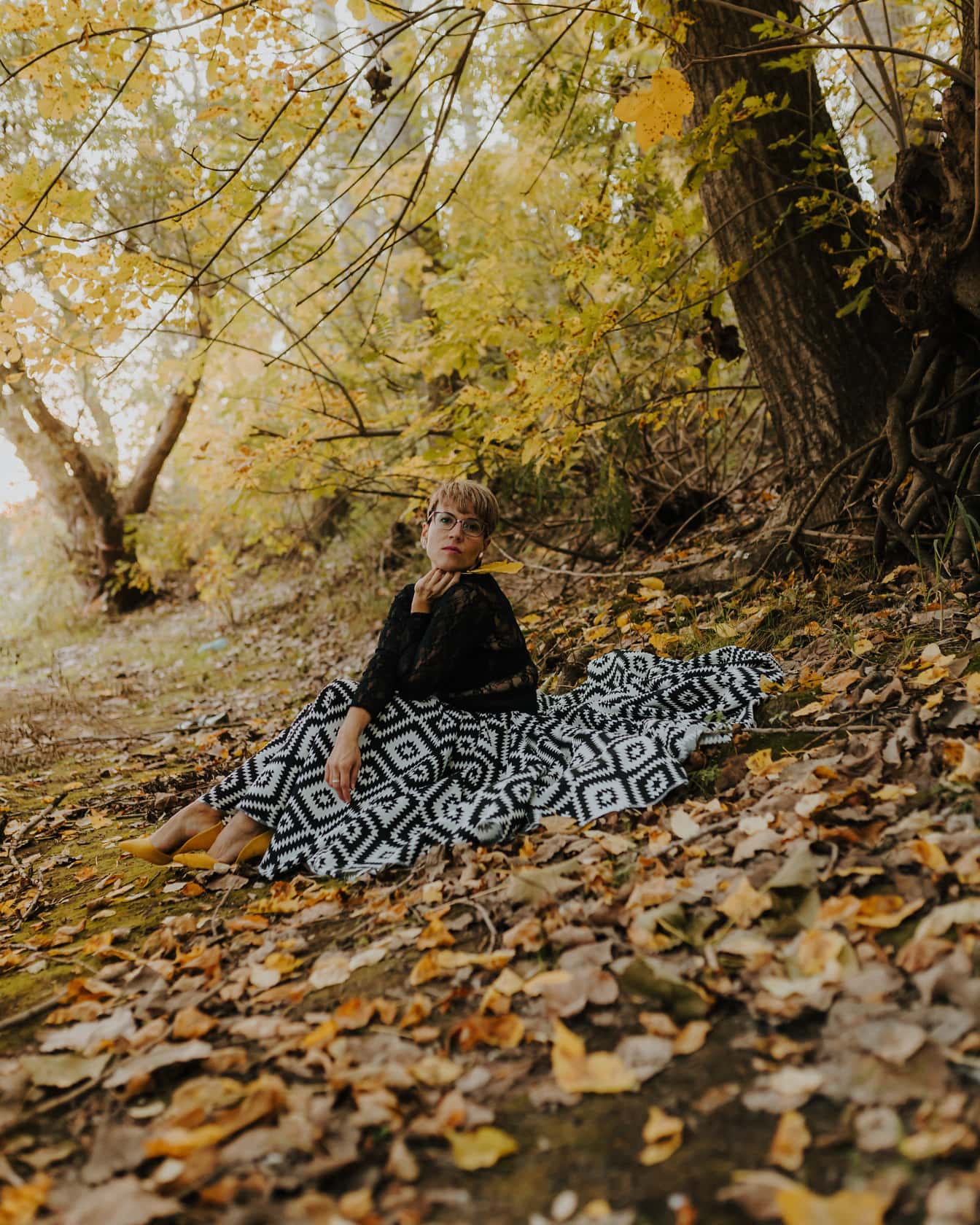 Elegante traje en blanco y negro en mujer joven en bosque de otoño