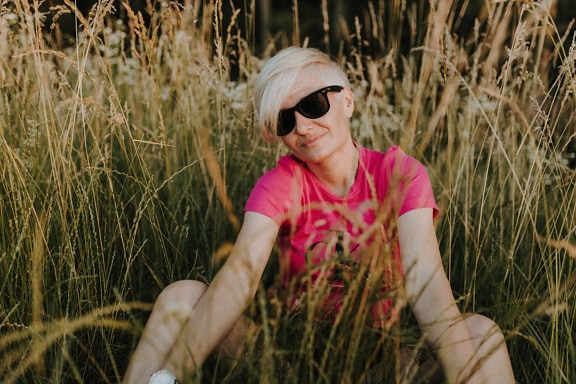 Portrait of adorable blonde sitting in meadow