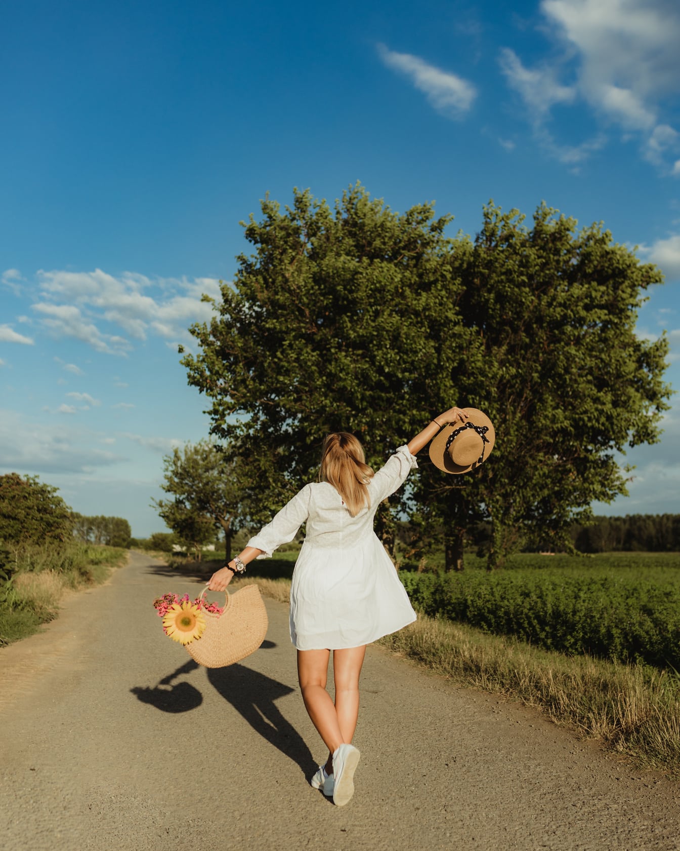 Счастливая молодая женщина на дороге с плетеной корзиной