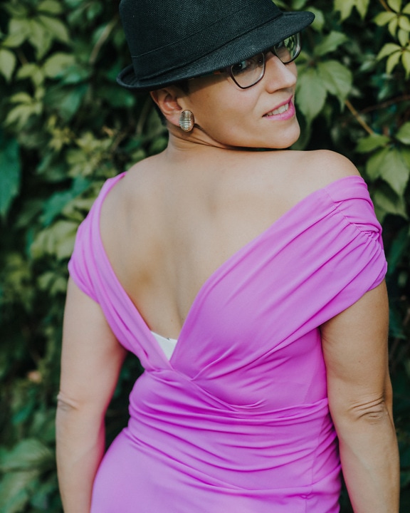 Przystojna kobieta w kapeluszu i fioletowej sukience uśmiechnięta