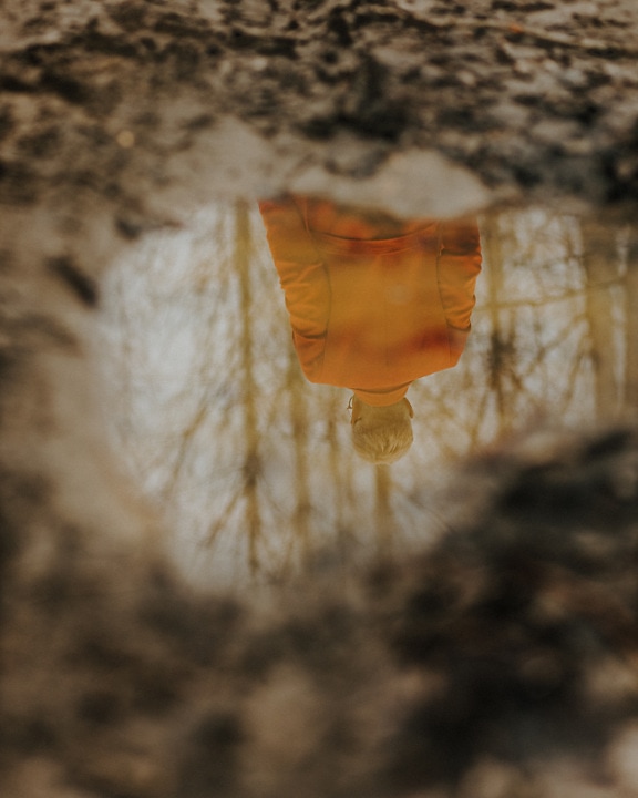 Reflection of person in small pond on ground