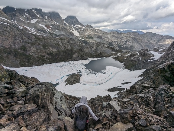 Extreme mountain climber on rocky mountains with frozen lake