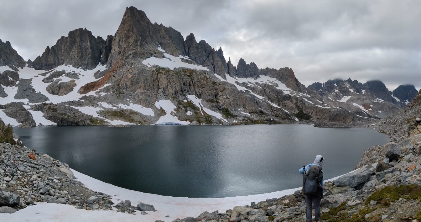Turista si užívá panorama břehu jezera za chladného počasí