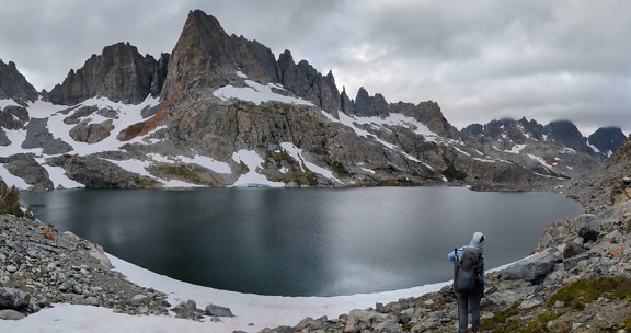 Турист наслаждается панорамой берега озера в холодную погоду