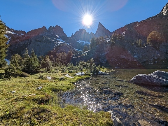 Sole splendente in montagna vicino al fiume roccioso