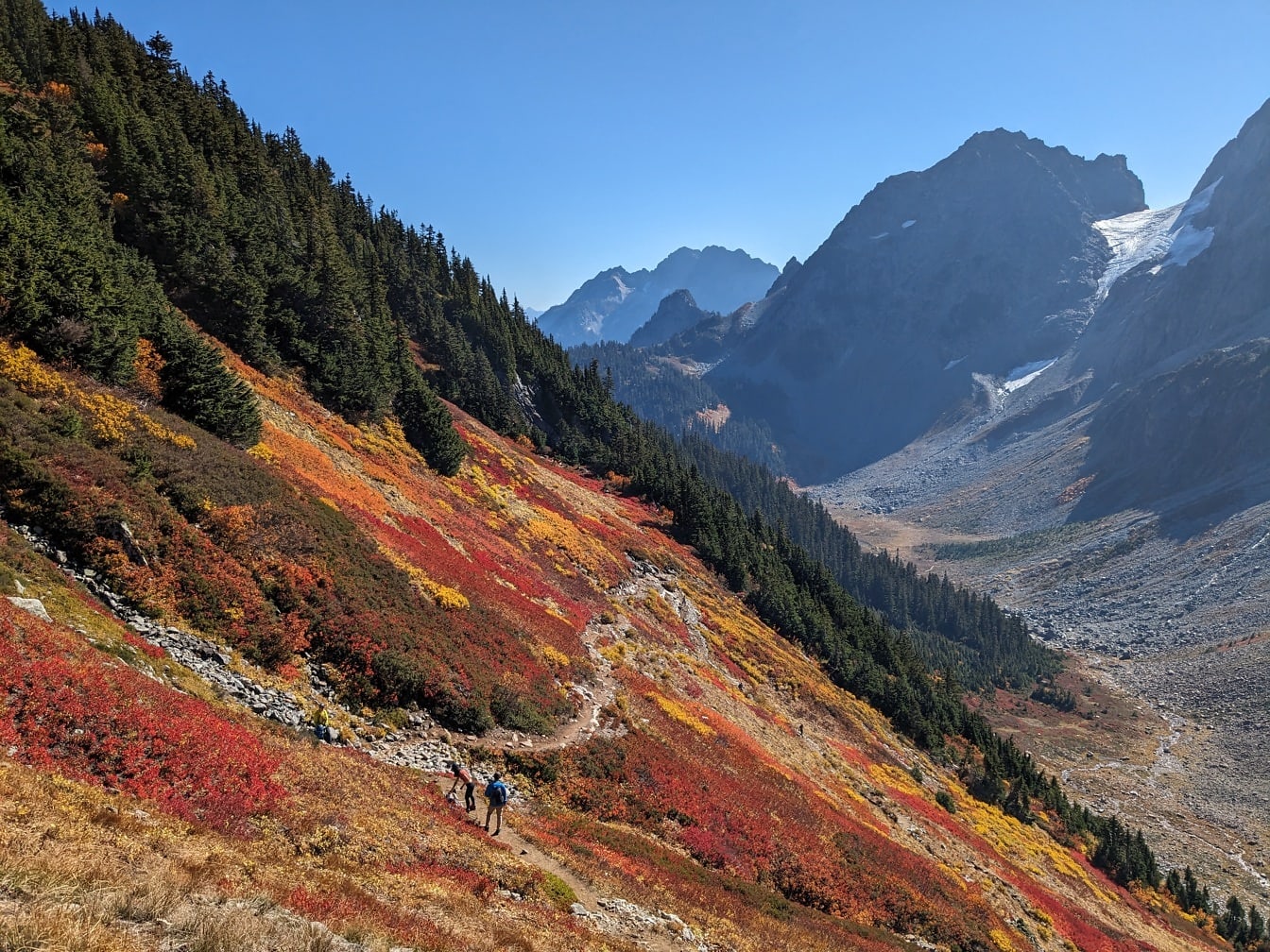 Alpiniști pe pârtia galbenă portocalie în sezonul de toamnă