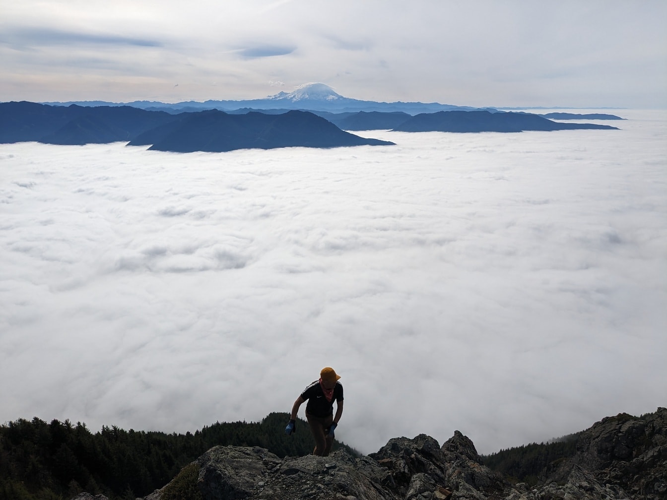 Alpinista wspinający się ponad białymi chmurami