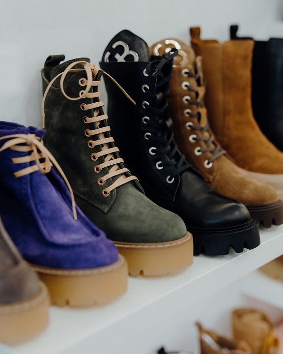 Many fancy leather boots on shelf close-up