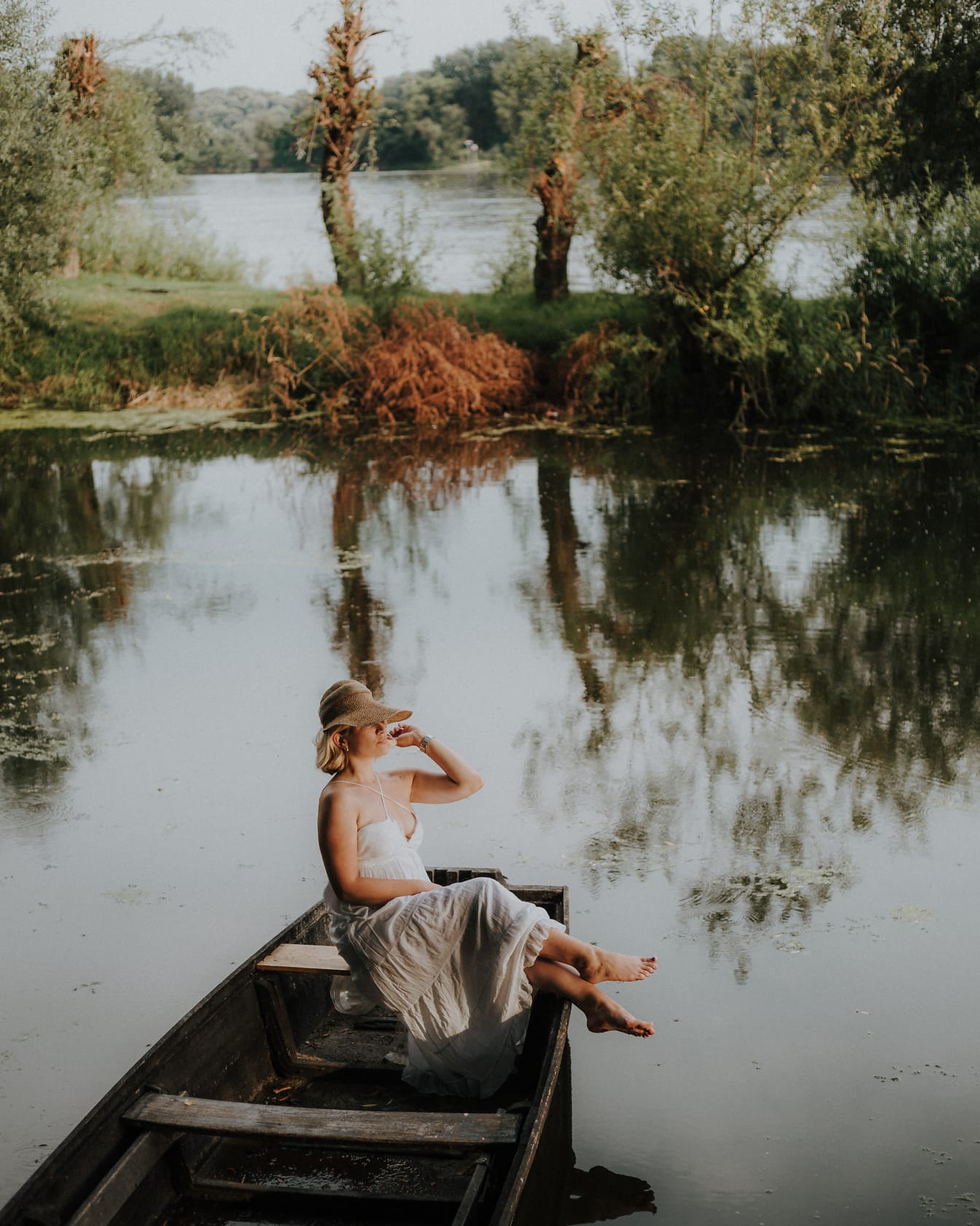 Elegante Frau posiert im Kleid und sitzt im Boot