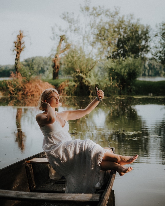 Przystojna blondynka pozuje na łodzi nad jeziorem