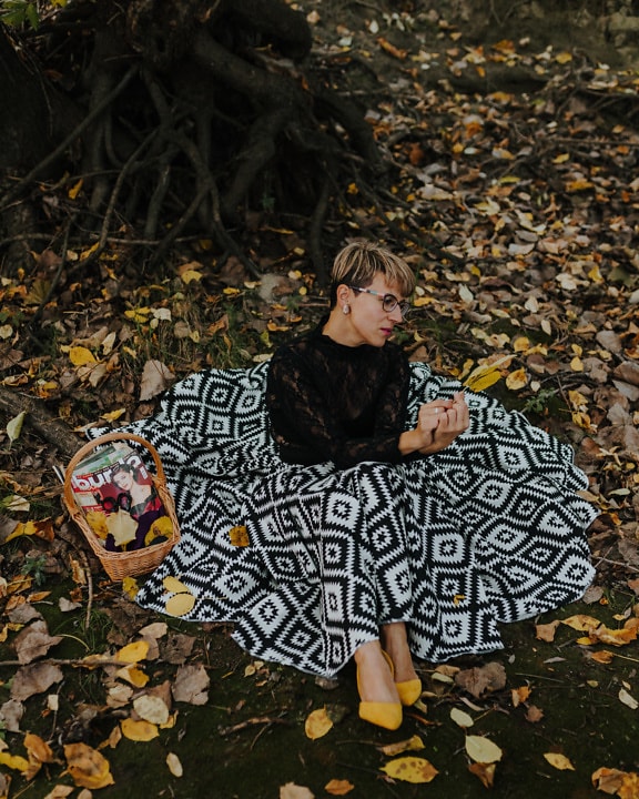 Beautiful short hair blonde sitting in elegant black and white dress in park