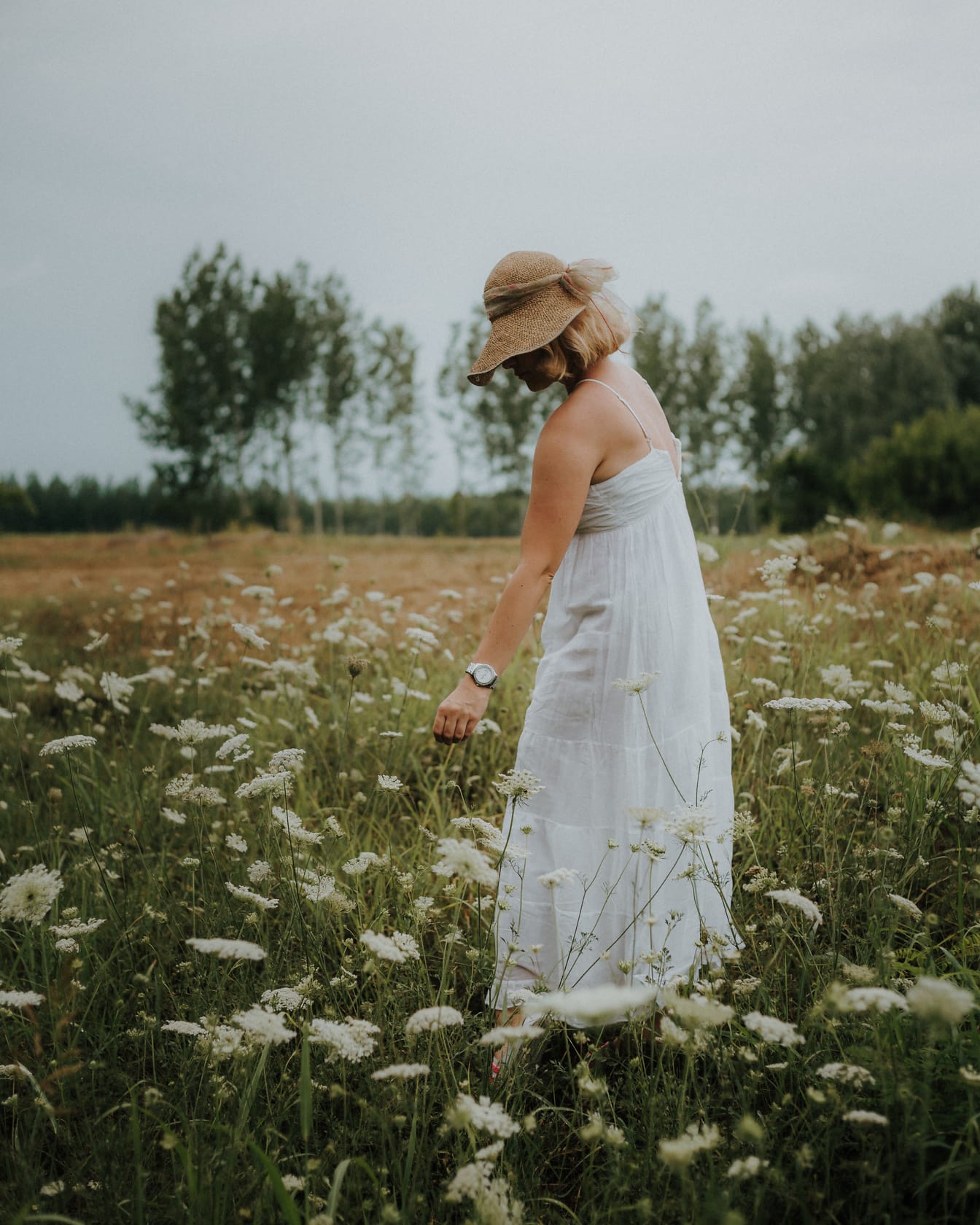 昔ながらの麦わら帽子と白いドレス、牧草地の写真モデルに