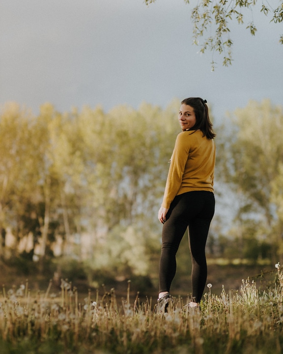 Adorable brunette in black pants and yellowish sweater