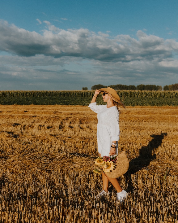 Cowgirl in straw hat and old fashioned dress in wheatfield