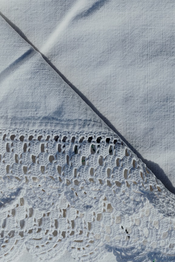 Czysta biała tkanina bawełniana z ręcznie robionymi ornamentami o fakturze zbliżenia