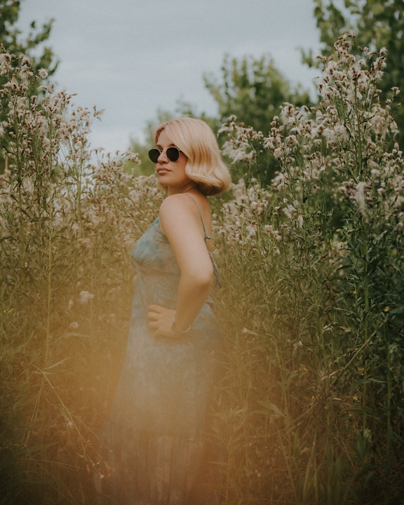 Elegant lady with sunglasses and pastel green dress in high grassland