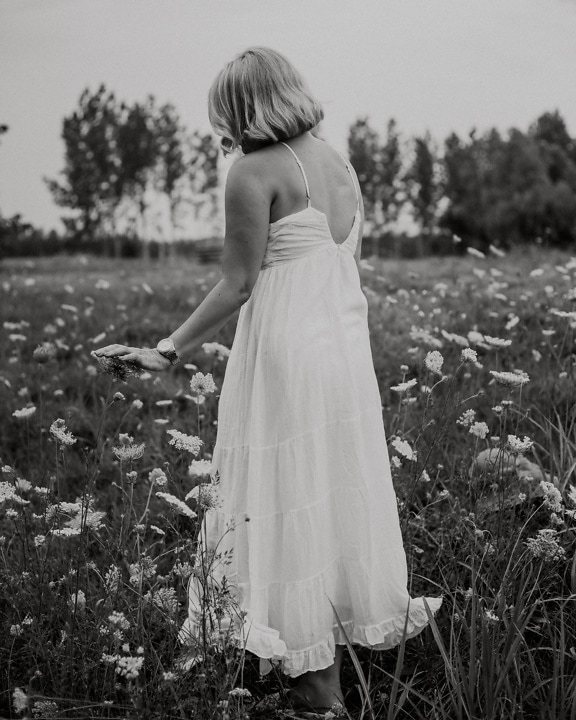White old-fashioned dress on blonde in meadow monochrome photo