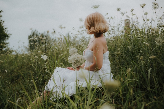 草原で白いドレスでポーズをとっているゴージャスなブロンド