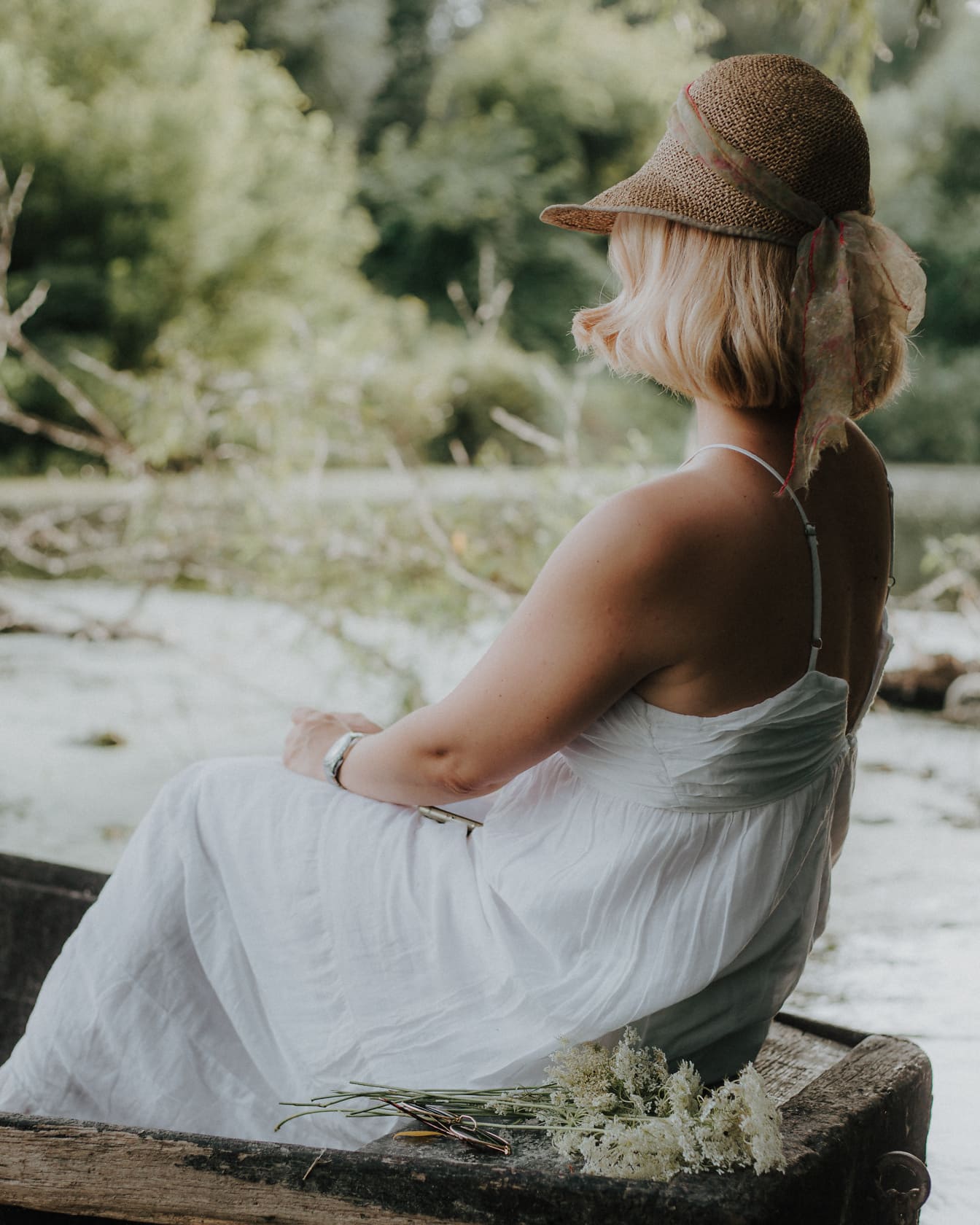 Klasyczna biała sukienka i słomkowy kapelusz na fotomodelce