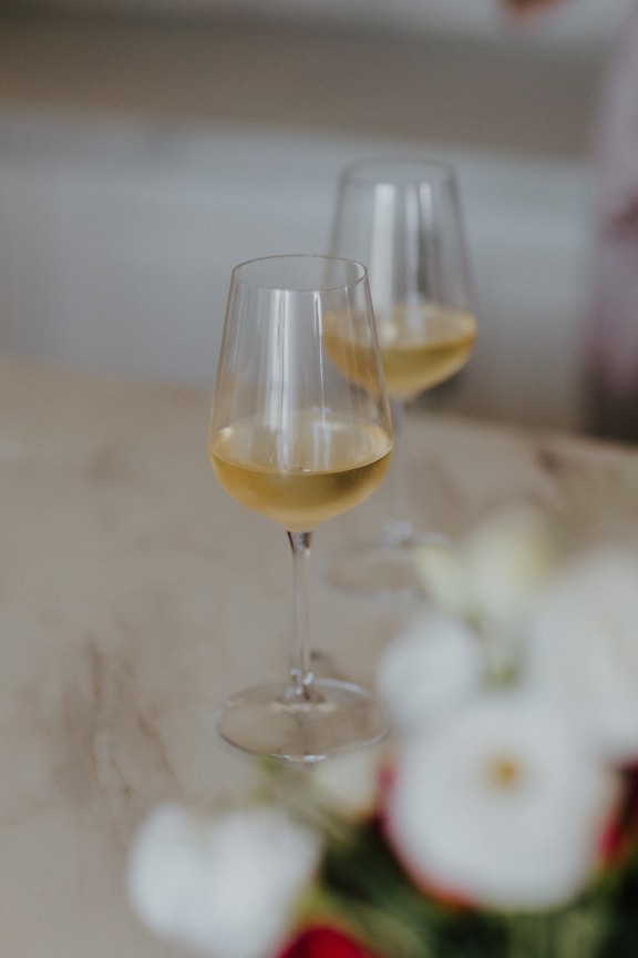Elegant crystal glasses with white wine on table