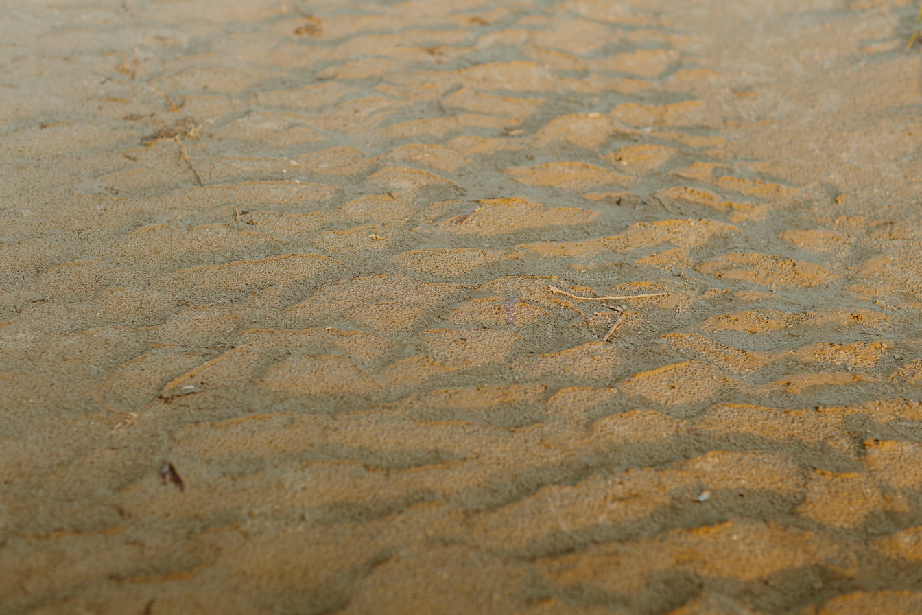 황갈색의 더러운 마른 모래가 그림자 클로즈업으로 틈새에 있습니다.