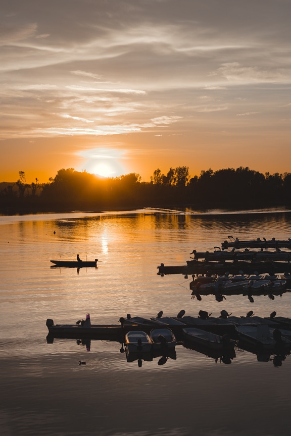 Gyönyörű fénykép sárgásbarna napfelkeltéről a tóparti kikötőben