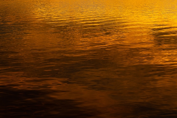 Pantulan matahari terbenam oranye cerah, kuning di permukaan air