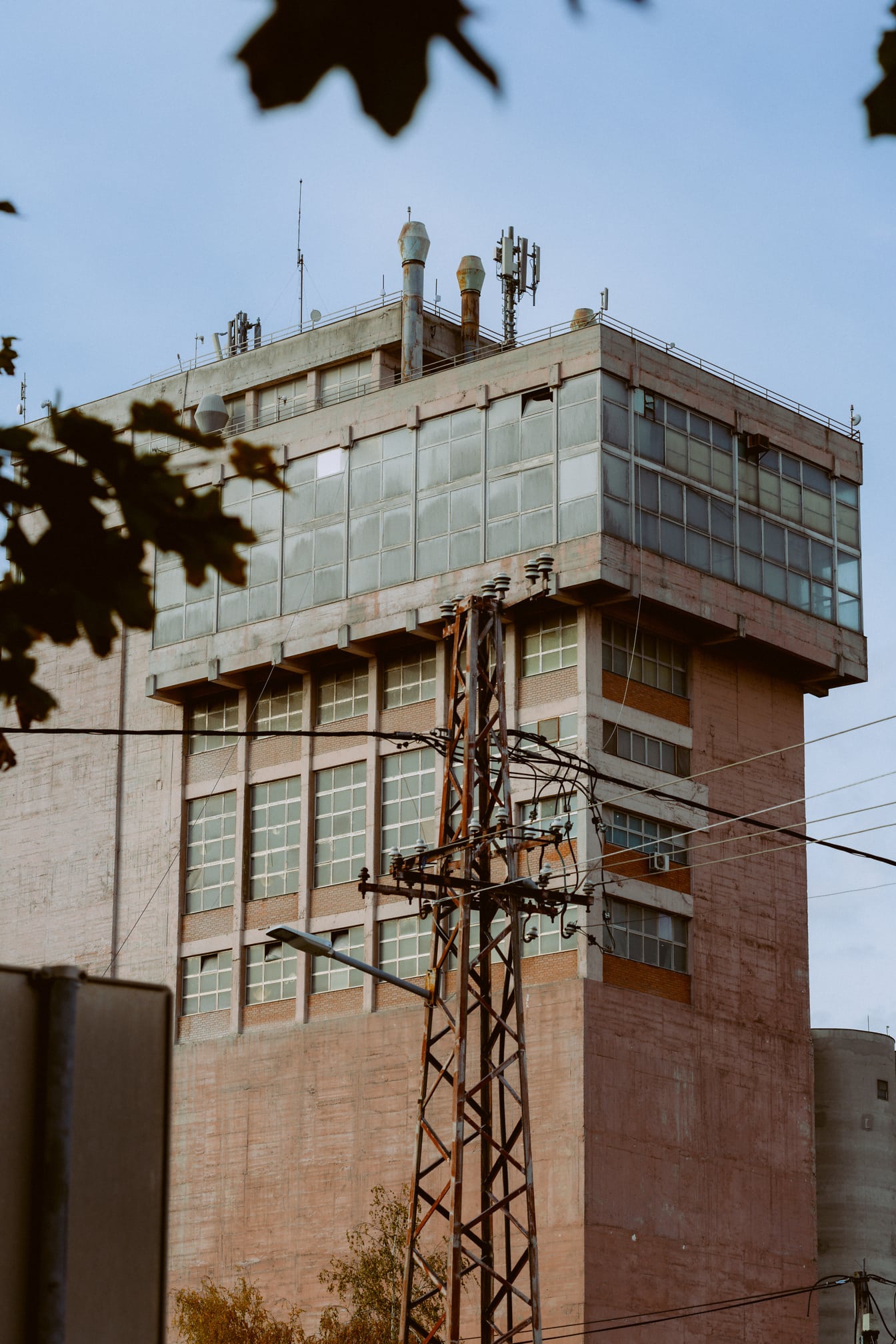 Torre eléctrica oxidada frente al edificio en estilo arquitectónico socialista