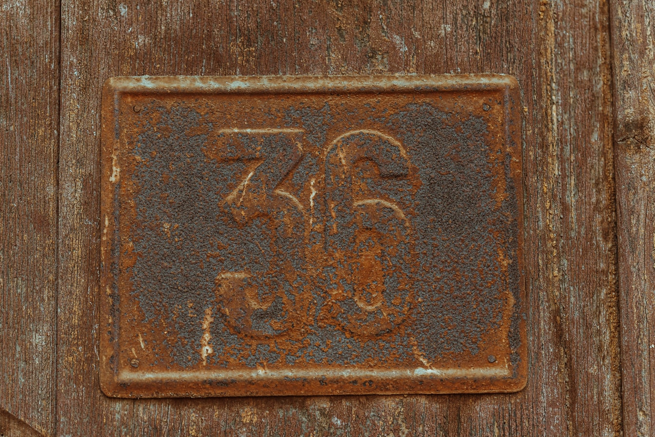 茶色の板に古い金属の錆びた数字