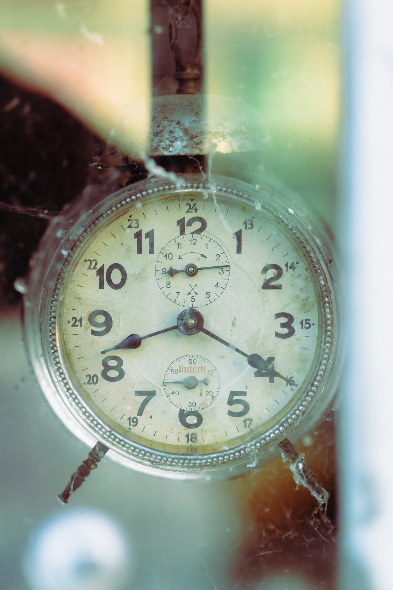 Valokuva vanhasta maalaismaisesta Staubdicht-kellosta, jossa hämähäkinseitti ja lasiheijastus