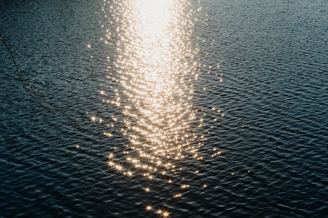 Kultaisen hehkun auringonsäteet heijastuvat veden pinnalle