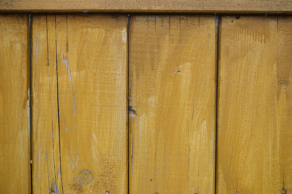 Yellowish brown paint on vertical wooden plans close-up texture