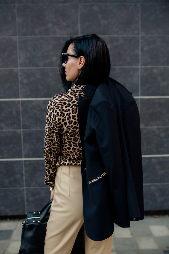 Femme d’affaires en pantalon beige et manteau noir tenue fantaisie