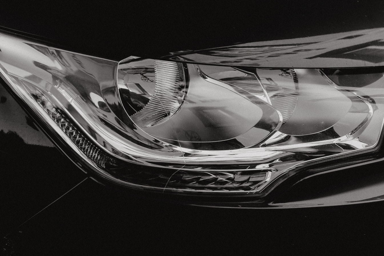 Zwart-wit foto van glanzende koplamp van auto