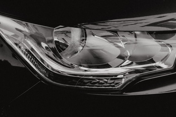 車の輝くヘッドライトのモノクロ写真