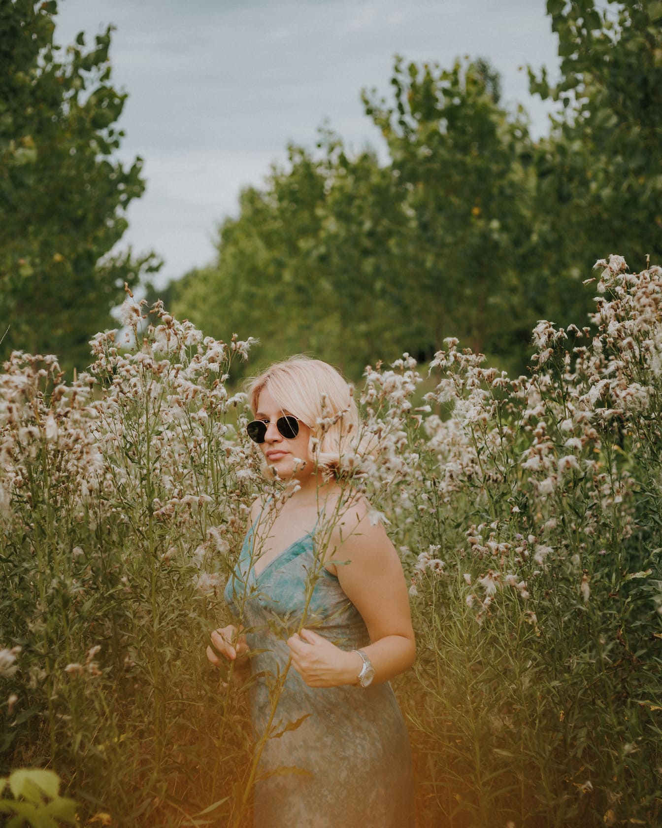 Nádherná blondínka pózujúca na lúke s vysokou trávou