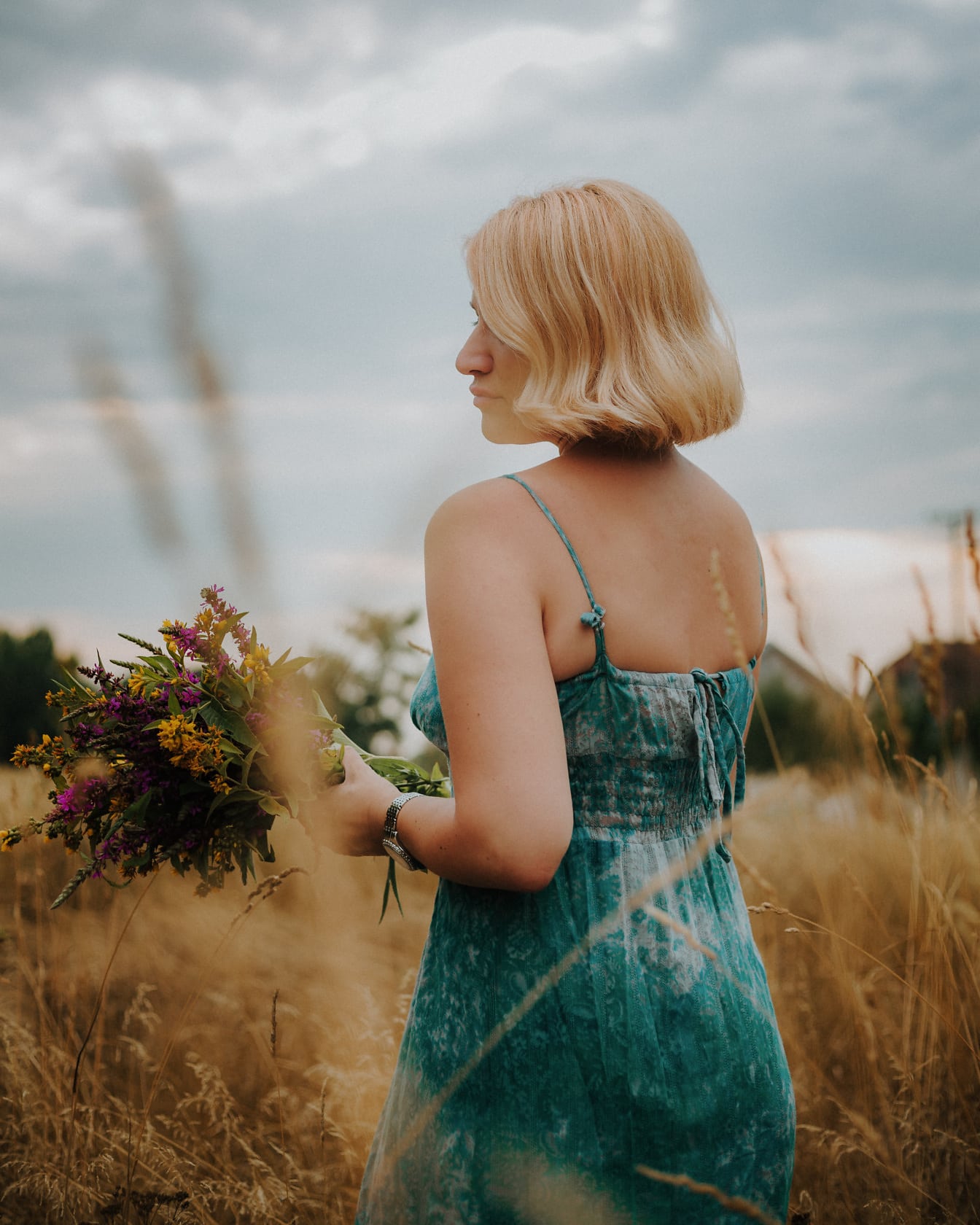 Green casual dress on blonde with bouqet of flowers in meadow