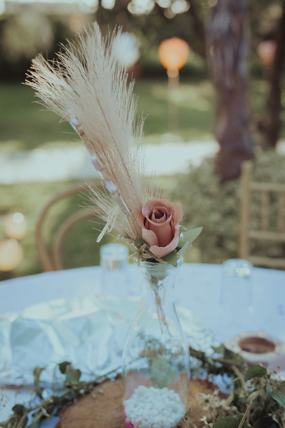 Pastelna ružičasta ruža u ukrasu stola od staklene vaze
