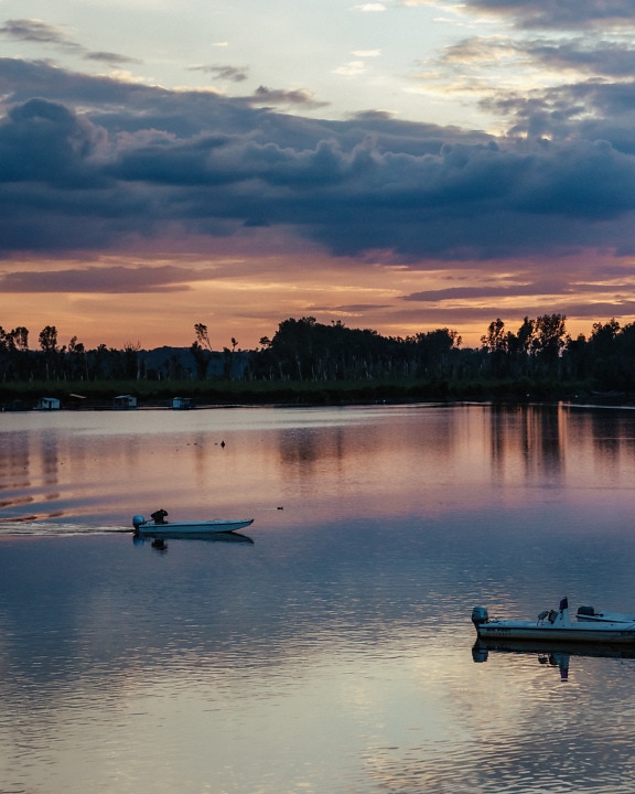 Bateaux de pêche blancs sur l’eau calme du lac au crépuscule