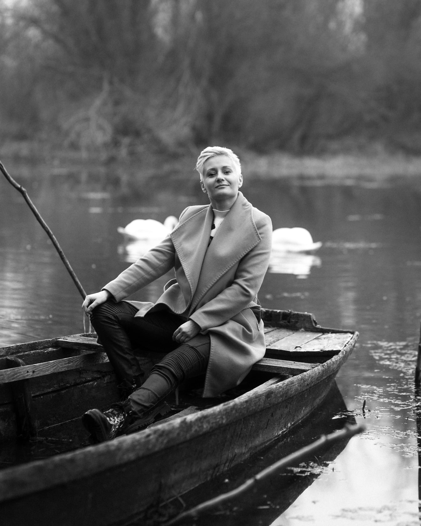 Monokromt portrett av attraktiv blondine som sitter i gammel båt