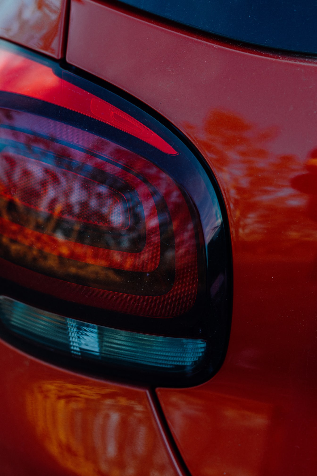 Tampilan close-up lampu belakang pada mobil metalik merah tua