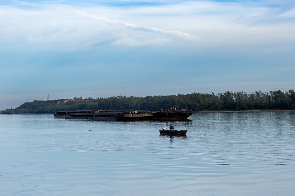 Barge ship in background and small fishing boat in foreground