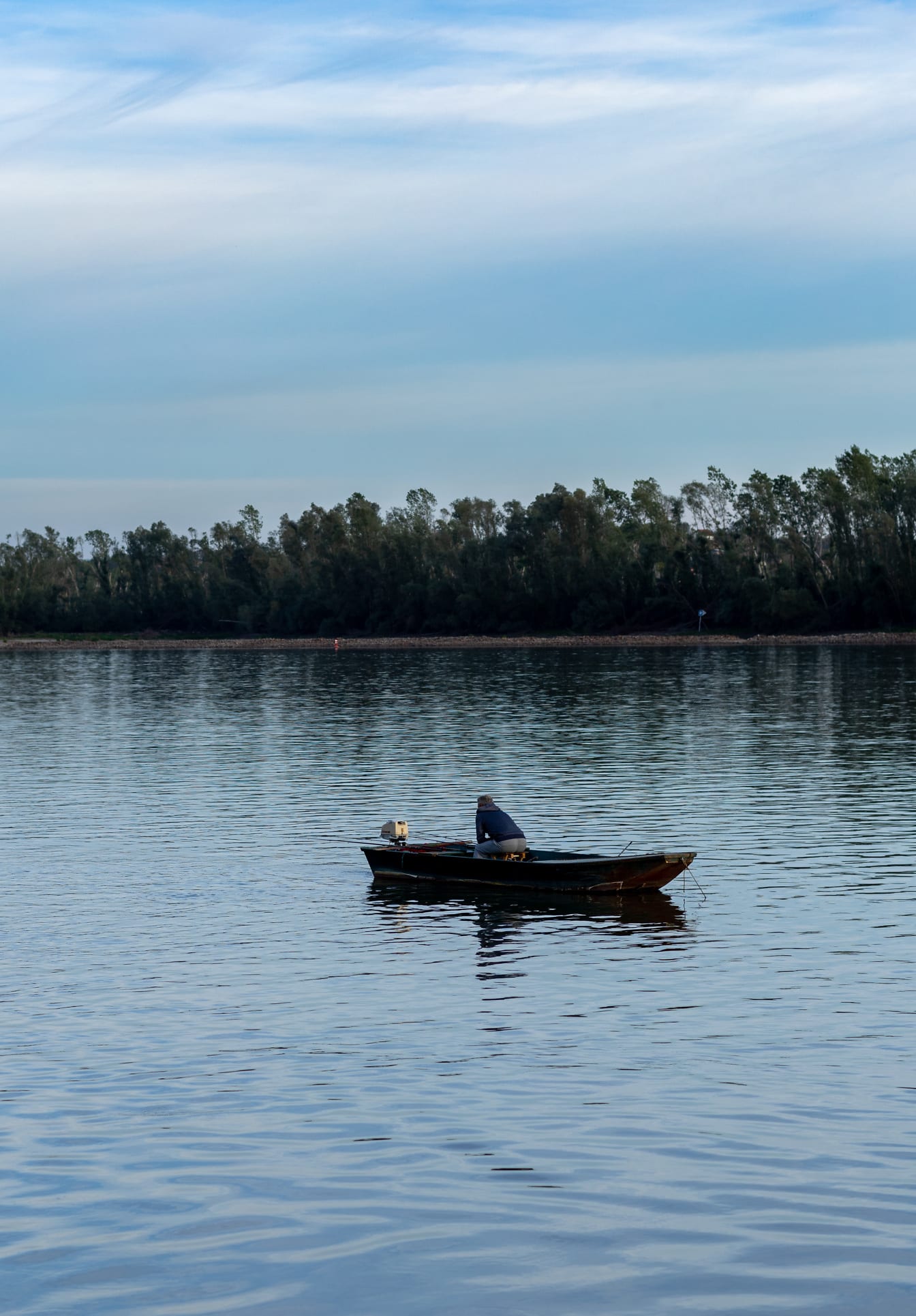 Рибар седи в дървена лодка и риболов