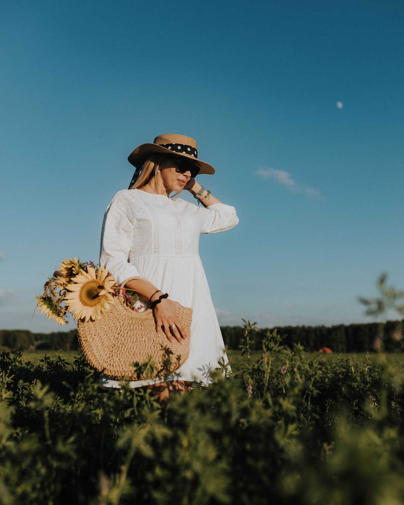 Model foto cu rochie albă de țară și pălărie de paie