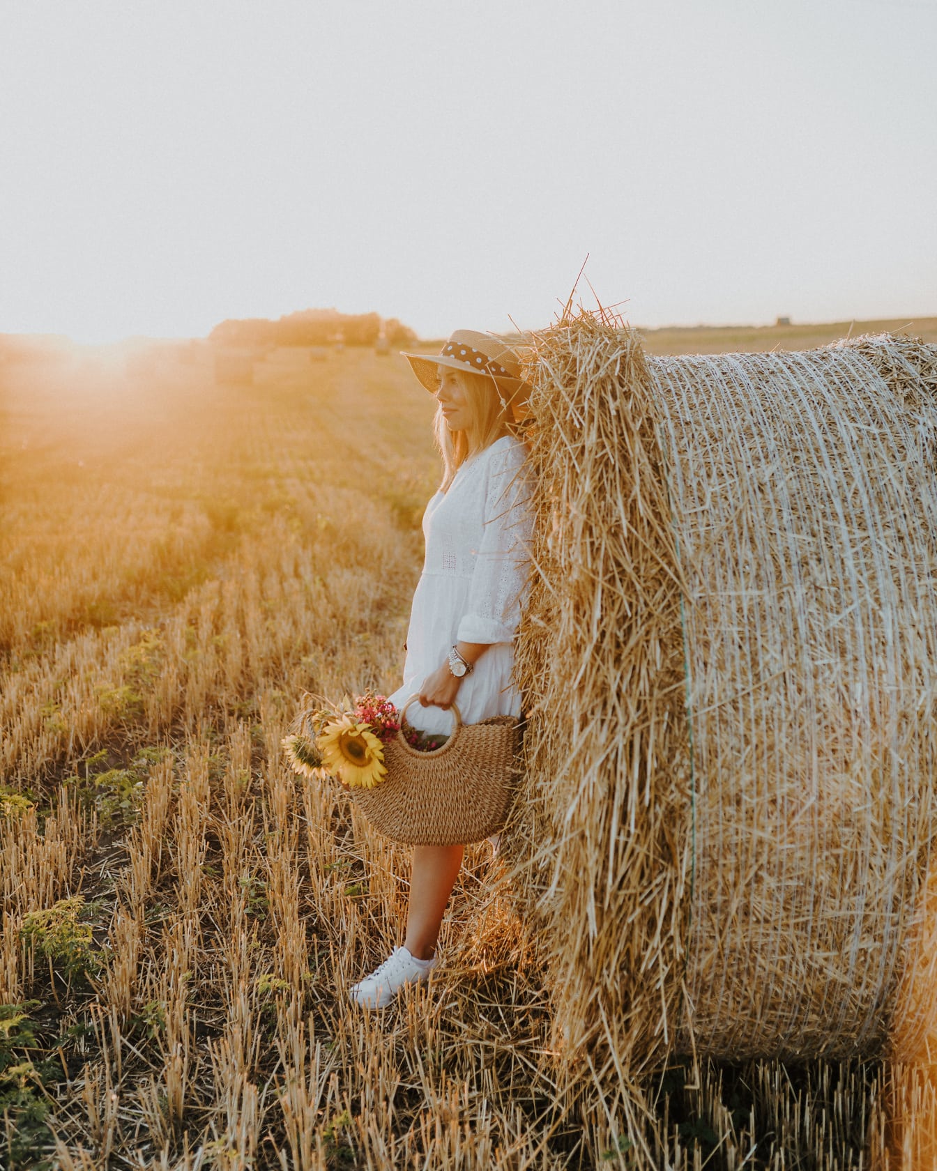 Красива млада жена, която се пече на слънце в какво поле от пшенична бала