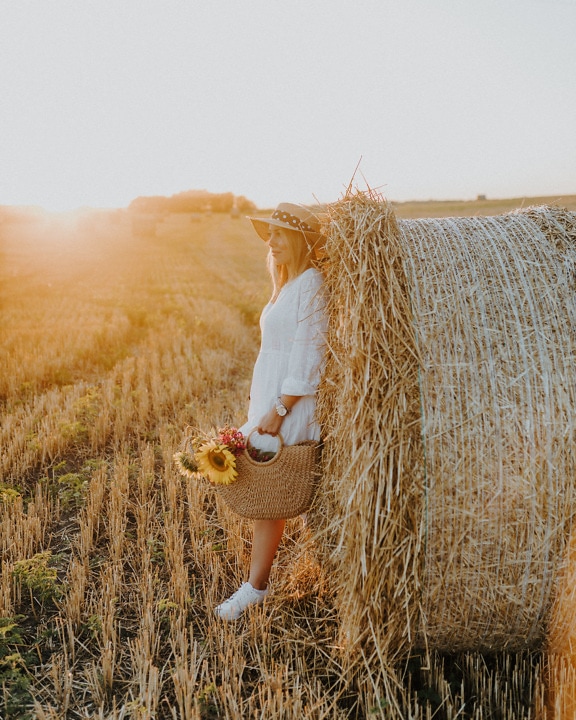 Hezká mladá žena opalující se na jakém poli u balíku pšenice
