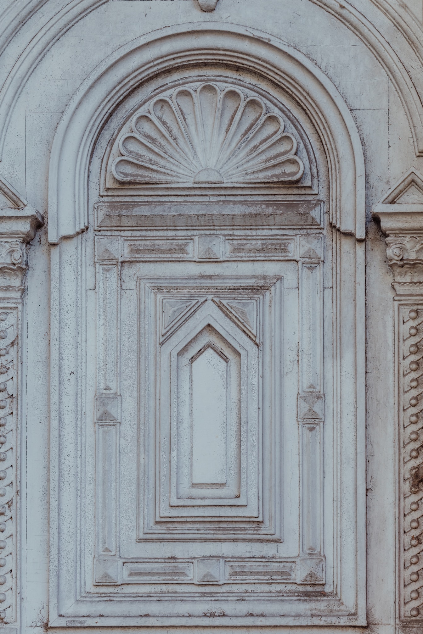 Weiße Vintage-Holzbogentür mit ornamentaler Dekoration