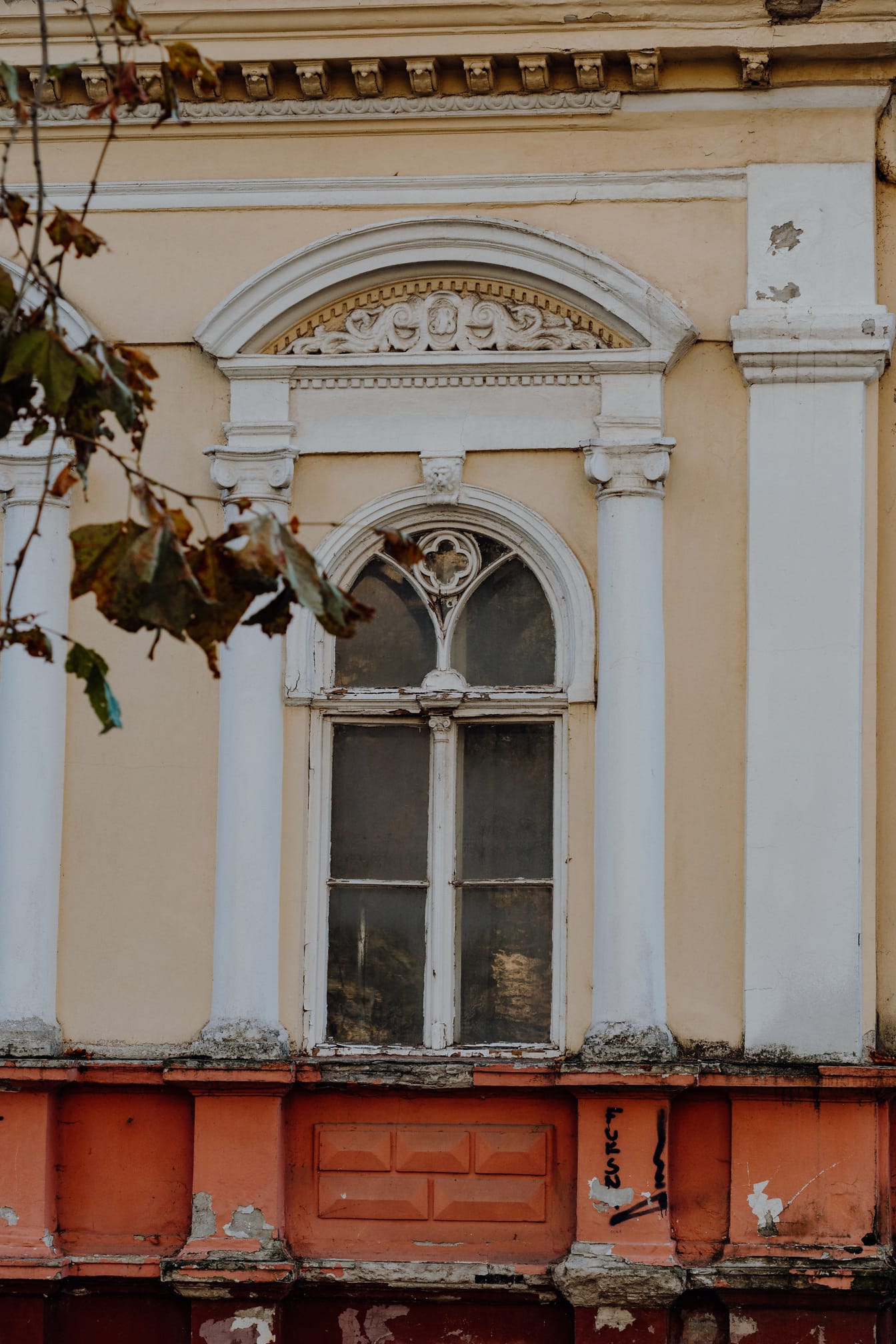 Fațada degradată a casei vechi cu fereastră din lemn și decor unic