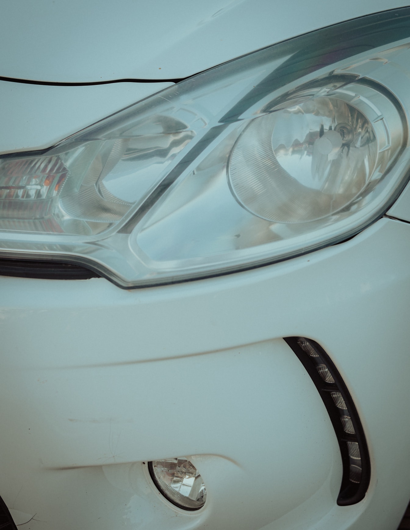 ホワイトメタリックのスポーツカーのクローズアップに透明なヘッドライト